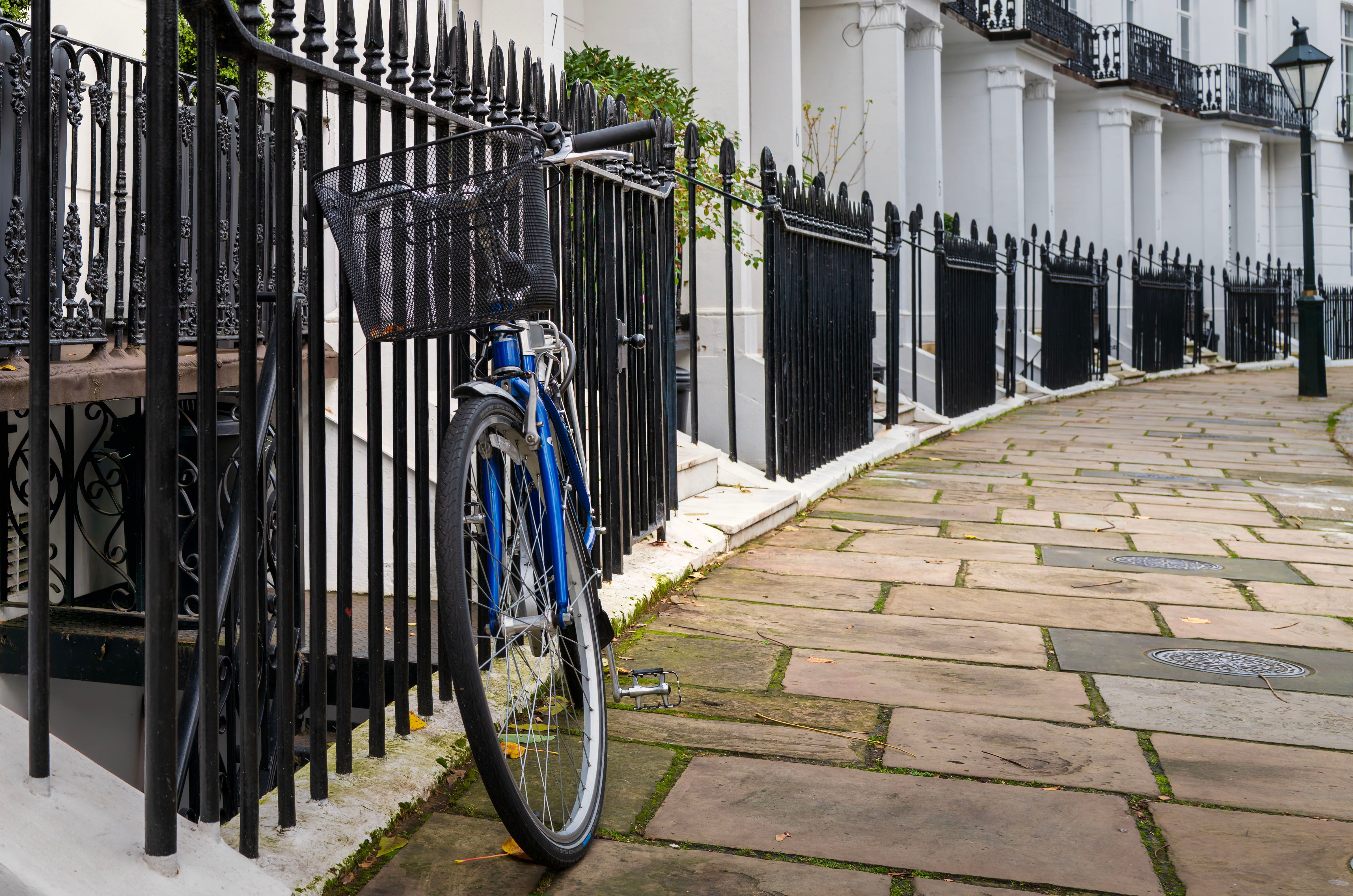 Charming urban scene of a bicycle beside wrought-iron railings on a quiet townhouse street.
