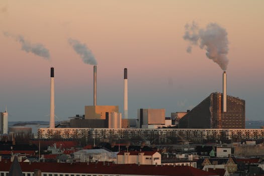View of a modern industrial factory with smokestacks in Copenhagen at sunset.