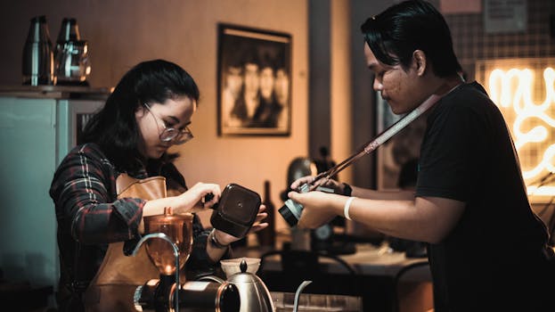 Baristas focused on brewing coffee using manual methods in a warm, inviting cafe setting.