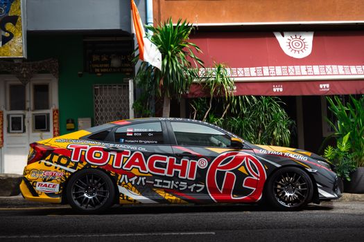 Vibrant race car parked in front of a cafe under bright daylight outdoors.