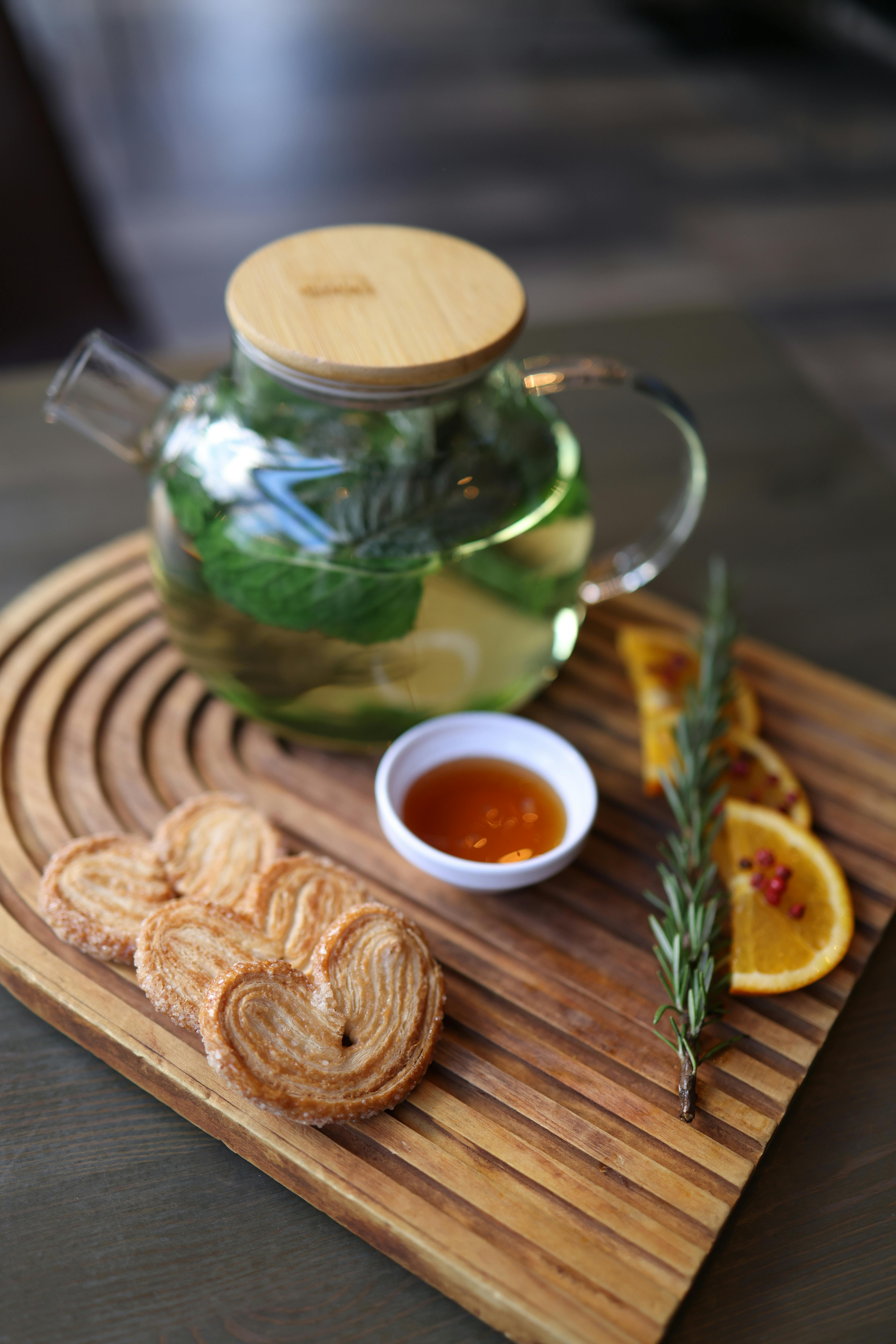 Aesthetic arrangement of herbal tea, fresh oranges, and pastries in a cozy setting.