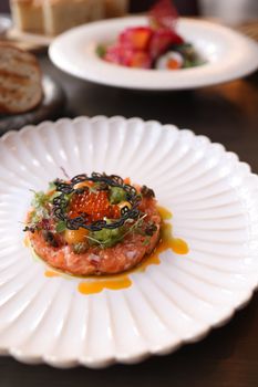 Close-up of a gourmet salmon tartare dish with garnishes served elegantly on a white plate, perfect for fine dining.