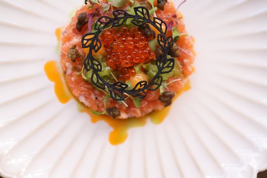 Top view of a beautifully plated gourmet salmon tartare with caviar and garnish, ideal for culinary arts content.