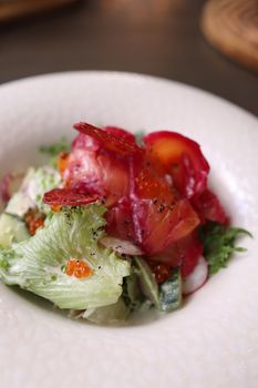 Colorful salmon salad featuring fresh greens and vibrant vegetables in a white bowl.