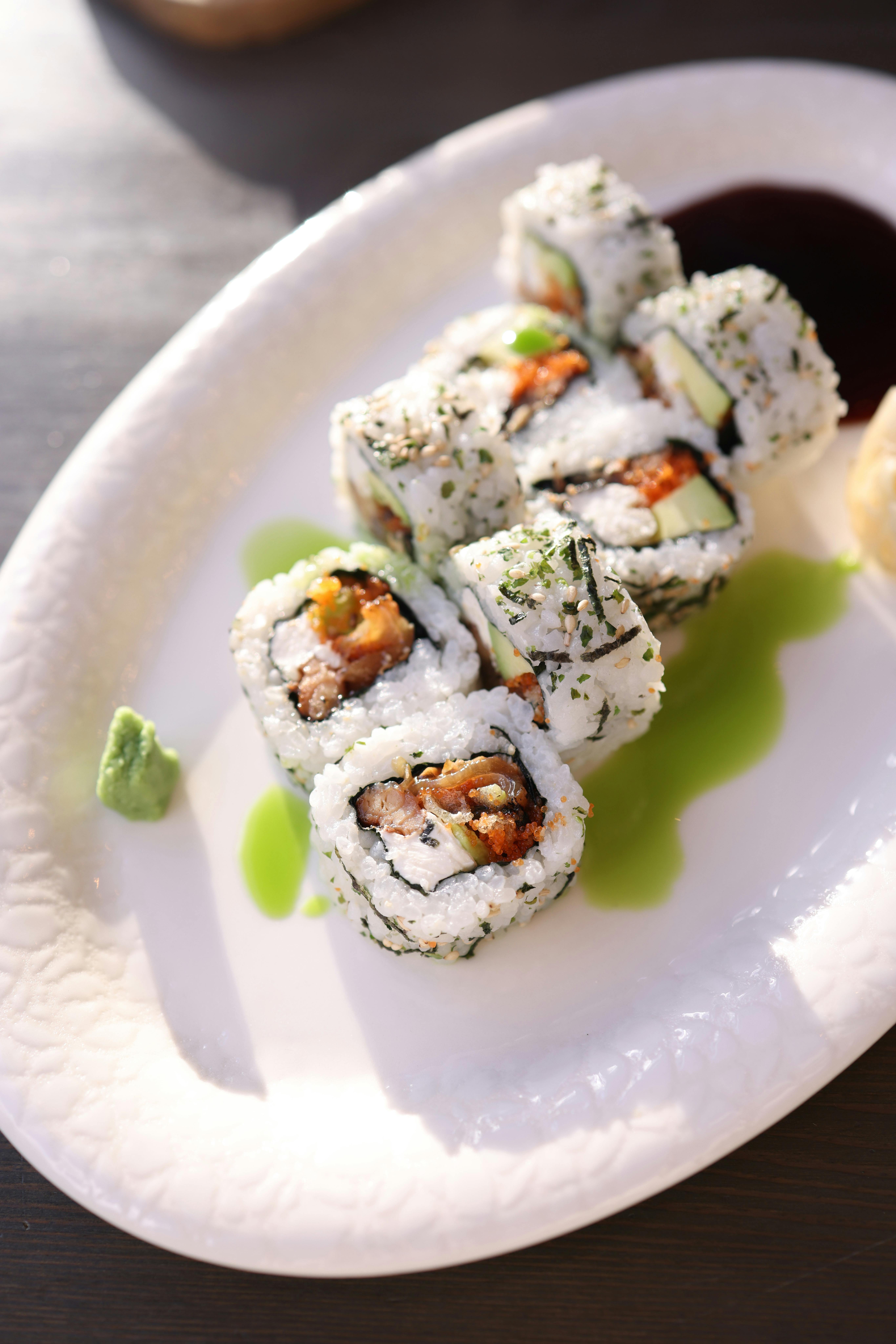 Close-up of sushi rolls with salmon and avocado on a white plate. Perfect for food lovers.