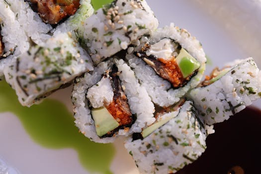 Delicious sushi rolls topped with sesame seeds, featuring avocado and fish, served on a plate.