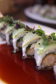 Delicious sushi roll topped with avocado, served on a plate with sauce, perfect for culinary inspiration.