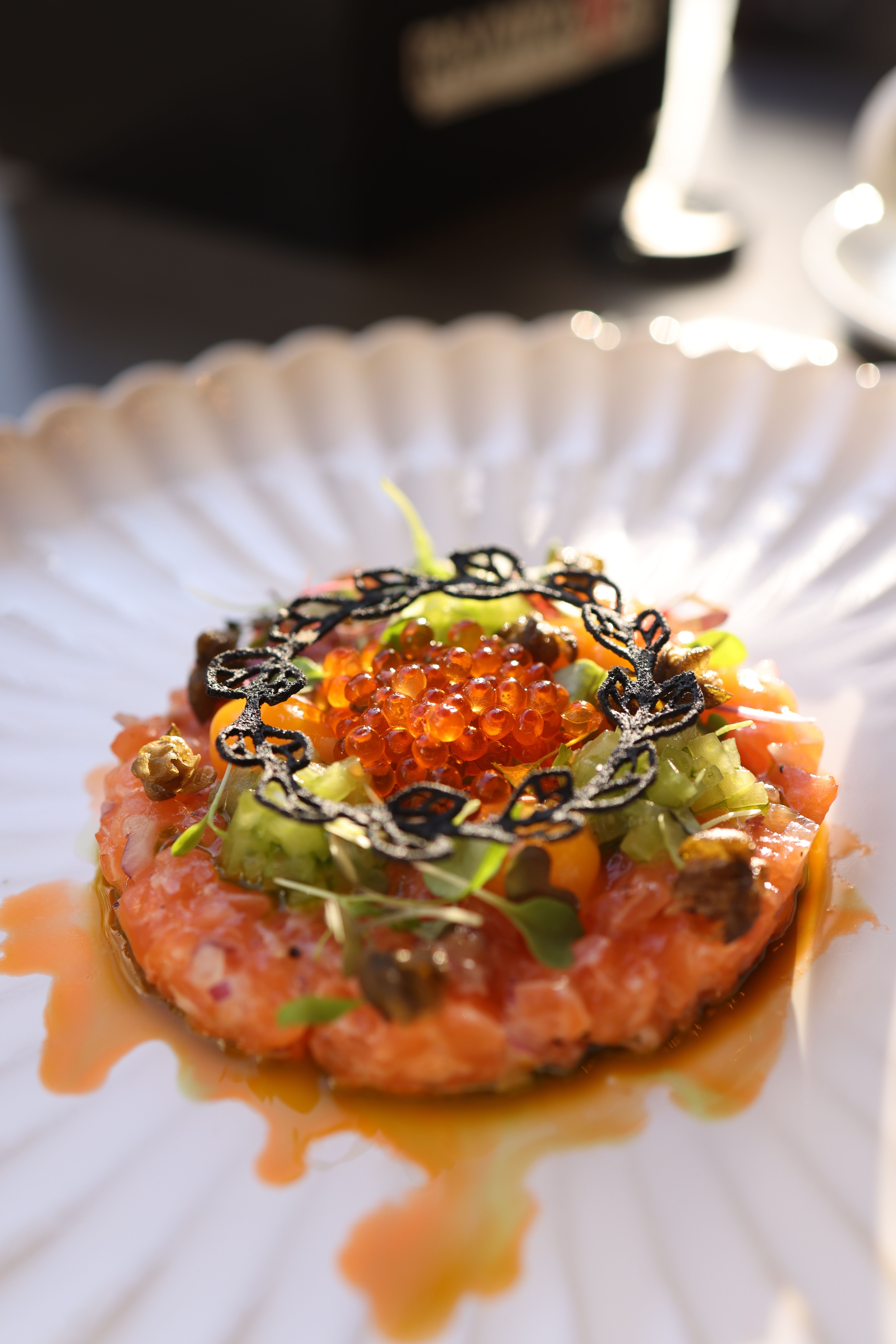 A beautifully plated salmon tartare with caviar and greens captured in natural light.