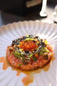 A beautifully plated salmon tartare with caviar and greens captured in natural light.