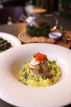 Elegant presentation of rolled fish on creamy risotto topped with caviar.