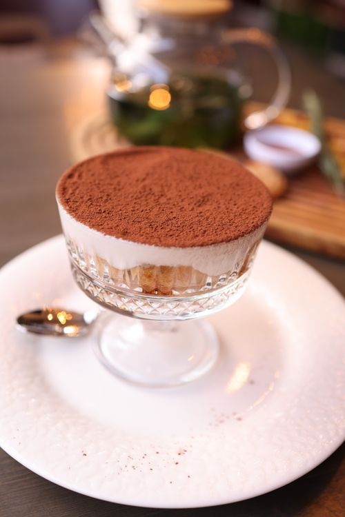 Free Elegant Tiramisu dessert in a crystal glass on a white plate, with soft focus background. Stock Photo