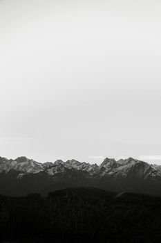 Stunning black and white photo of snowy mountain peaks under a vast sky.