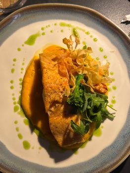 Delicious salmon fillet with vegetable garnish on a stylish plate.