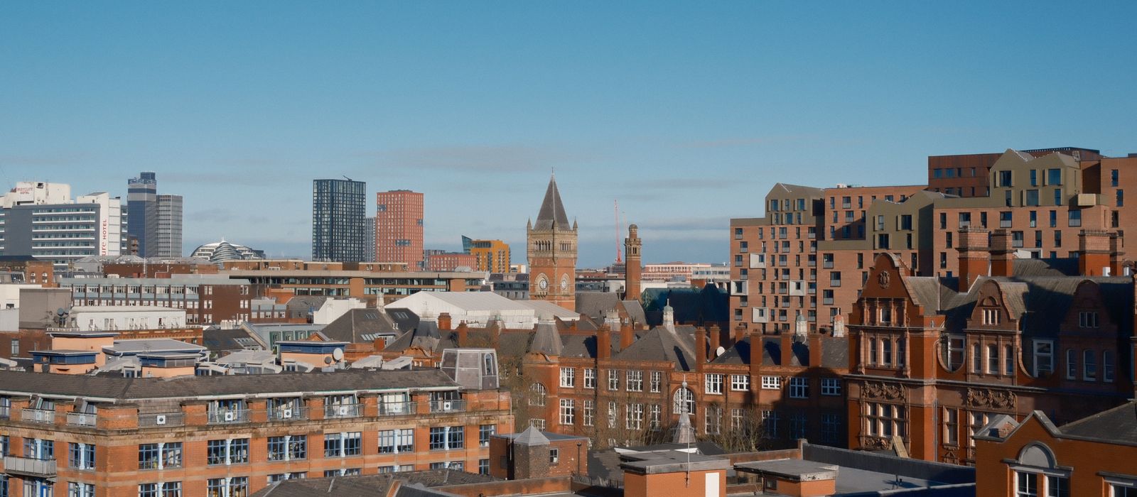 A vibrant view of Manchester showcasing modern and classic architecture under a clear sky. — flights from Pisa to Manchester
