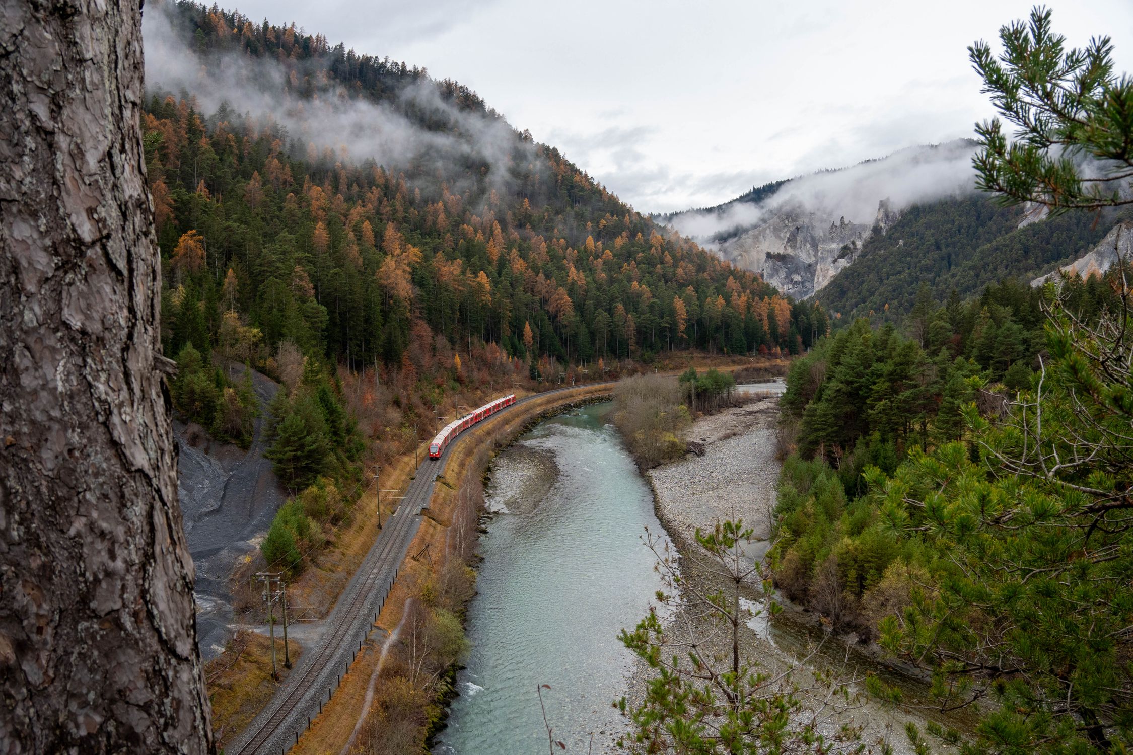 A scenic view of a train winding through the picturesque Safiental Valley in Switzerland during autumn.