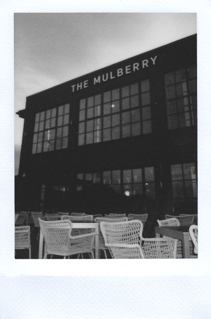 Black and white image of The Mulberry building with outdoor seating area.