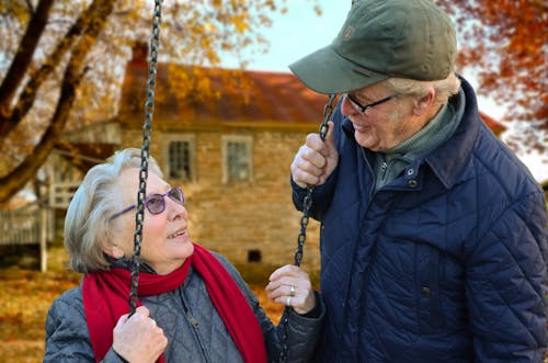 Uomo In Piedi Accanto Alla Donna Sull'altalena