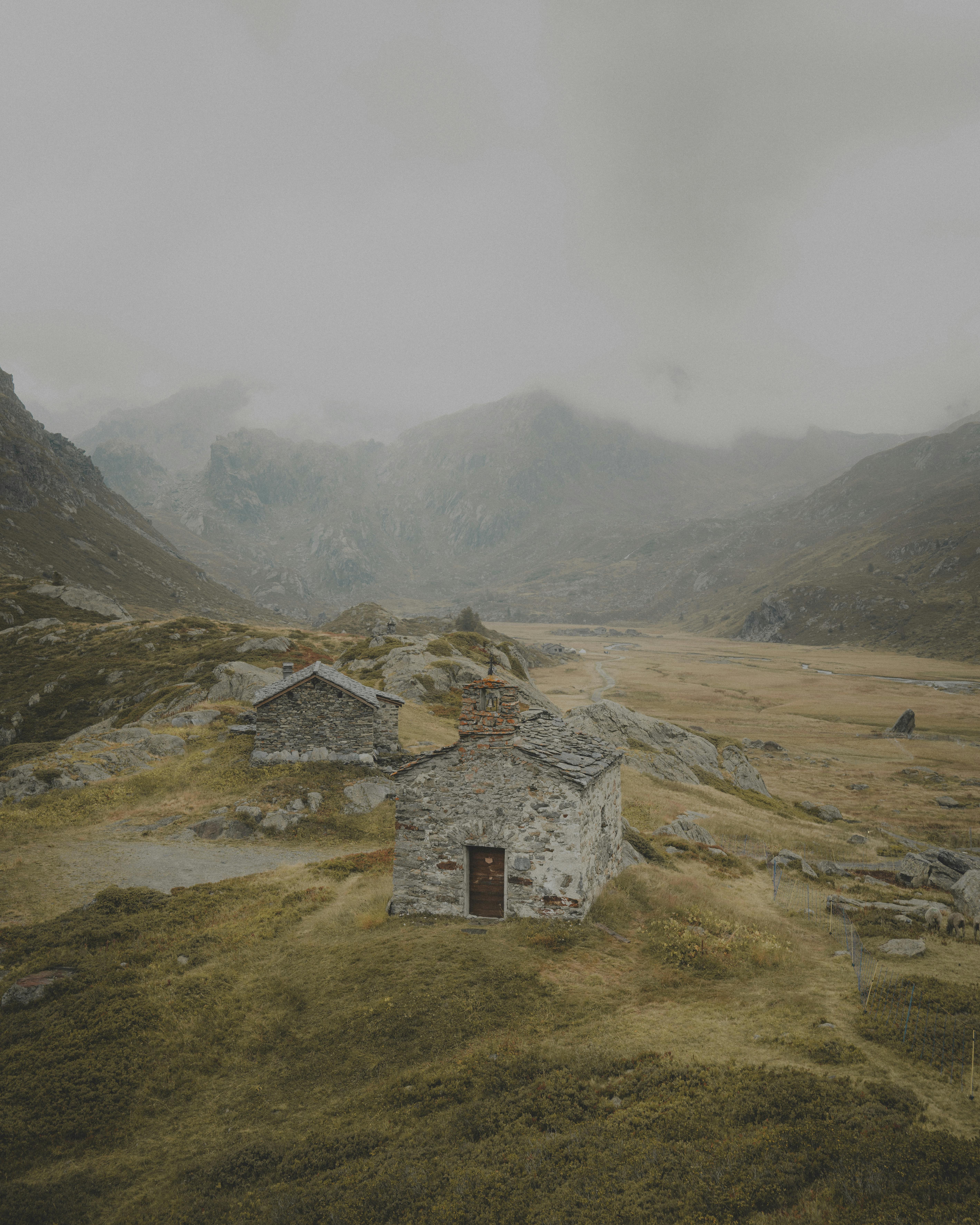 Moody landscape of stone houses in a misty French alpine valley.