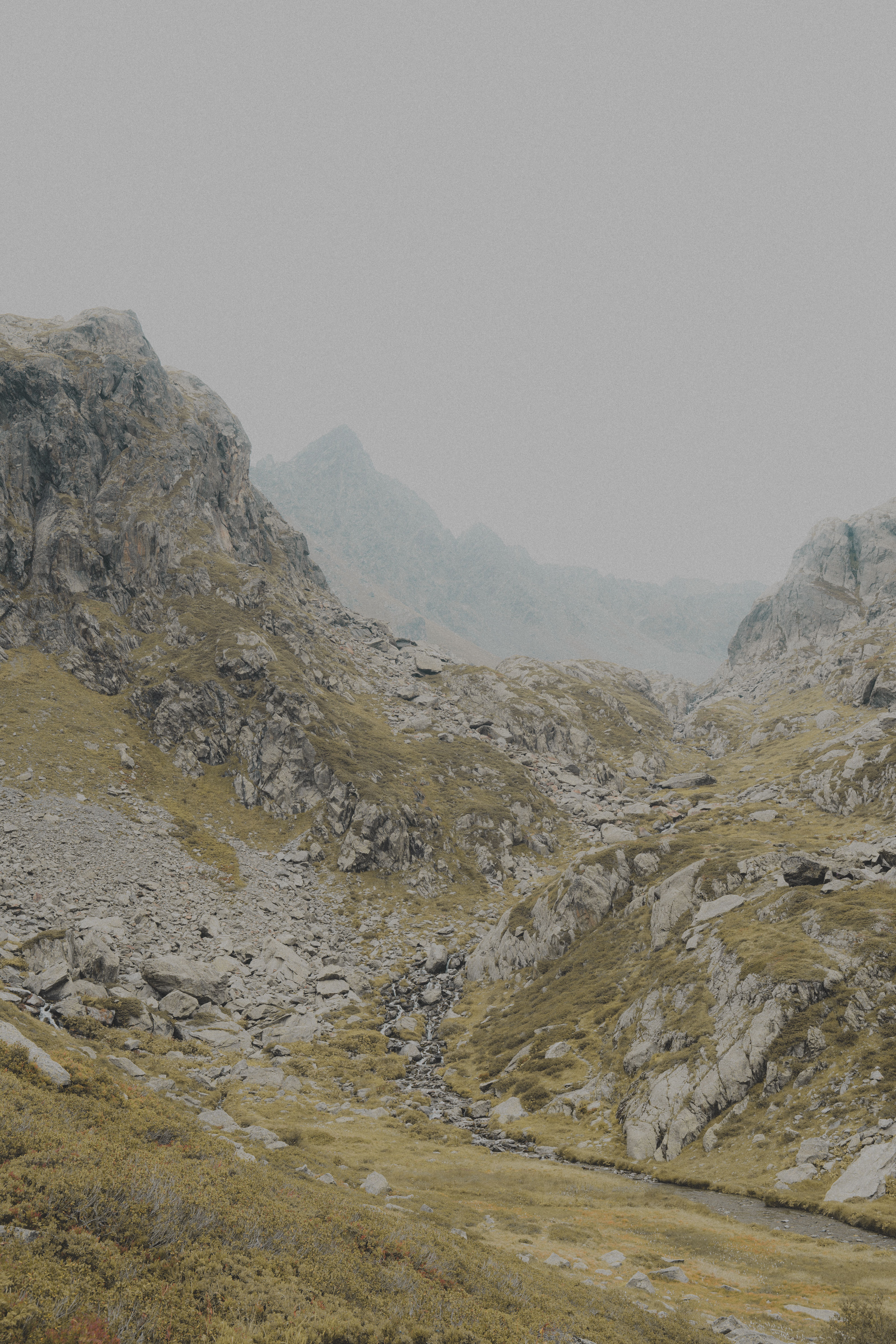 A moody, misty view of the rugged French Alps with rocky terrain and misty peaks.