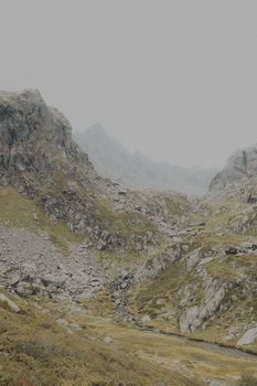 A moody, misty view of the rugged French Alps with rocky terrain and misty peaks.