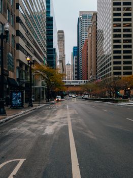 Wide downtown street flanked by tall skyscrapers in the daytime.