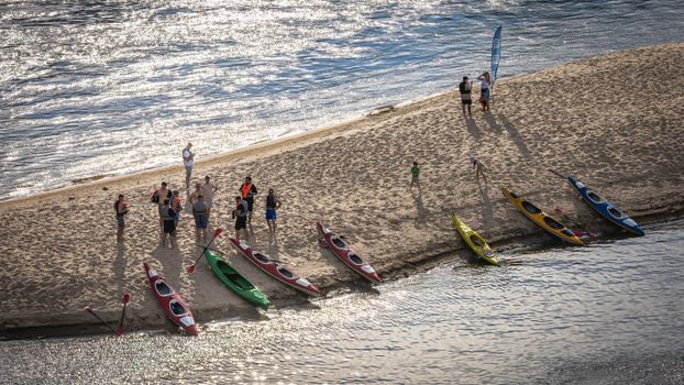 Aerial view of a group preparing kayaks on a sandy beach in Warsaw, Poland.