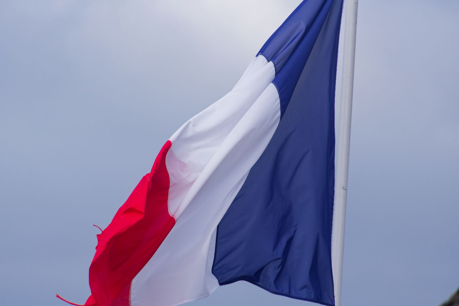 Drapeau tricolore français flottant sur un ciel gris couvert