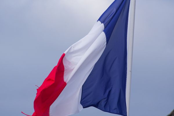 Drapeau tricolore français flottant sur un ciel gris couvert