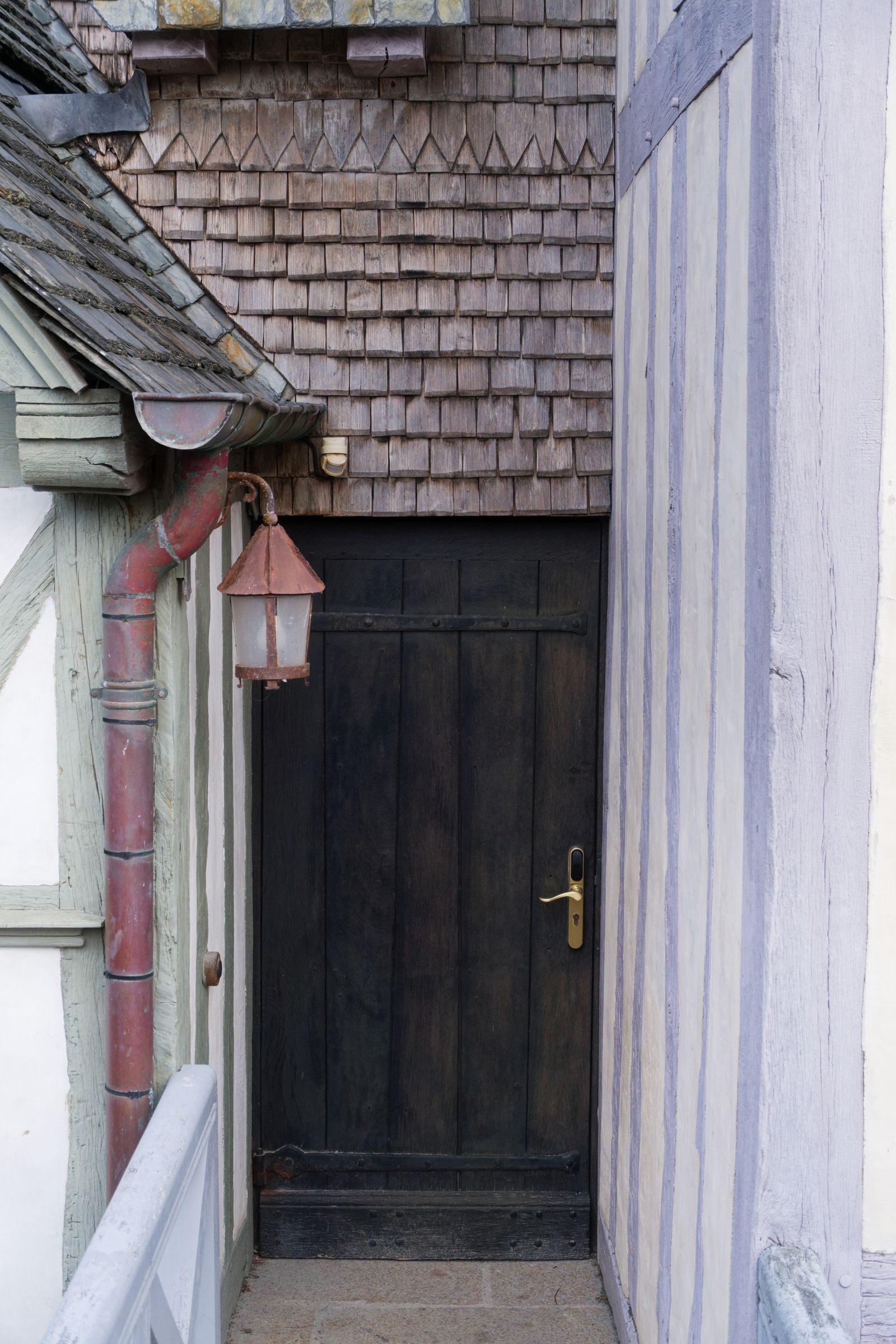 Rustic wooden door with lantern, framed by timber architecture, exudes old-world charm