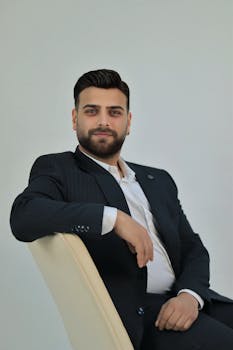 Young man in a formal suit confidently seated, exuding professionalism and poise.