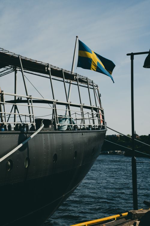 Free A historic ship with Swedish flag docked by the scenic waterfront, under clear blue skies. Stock Photo