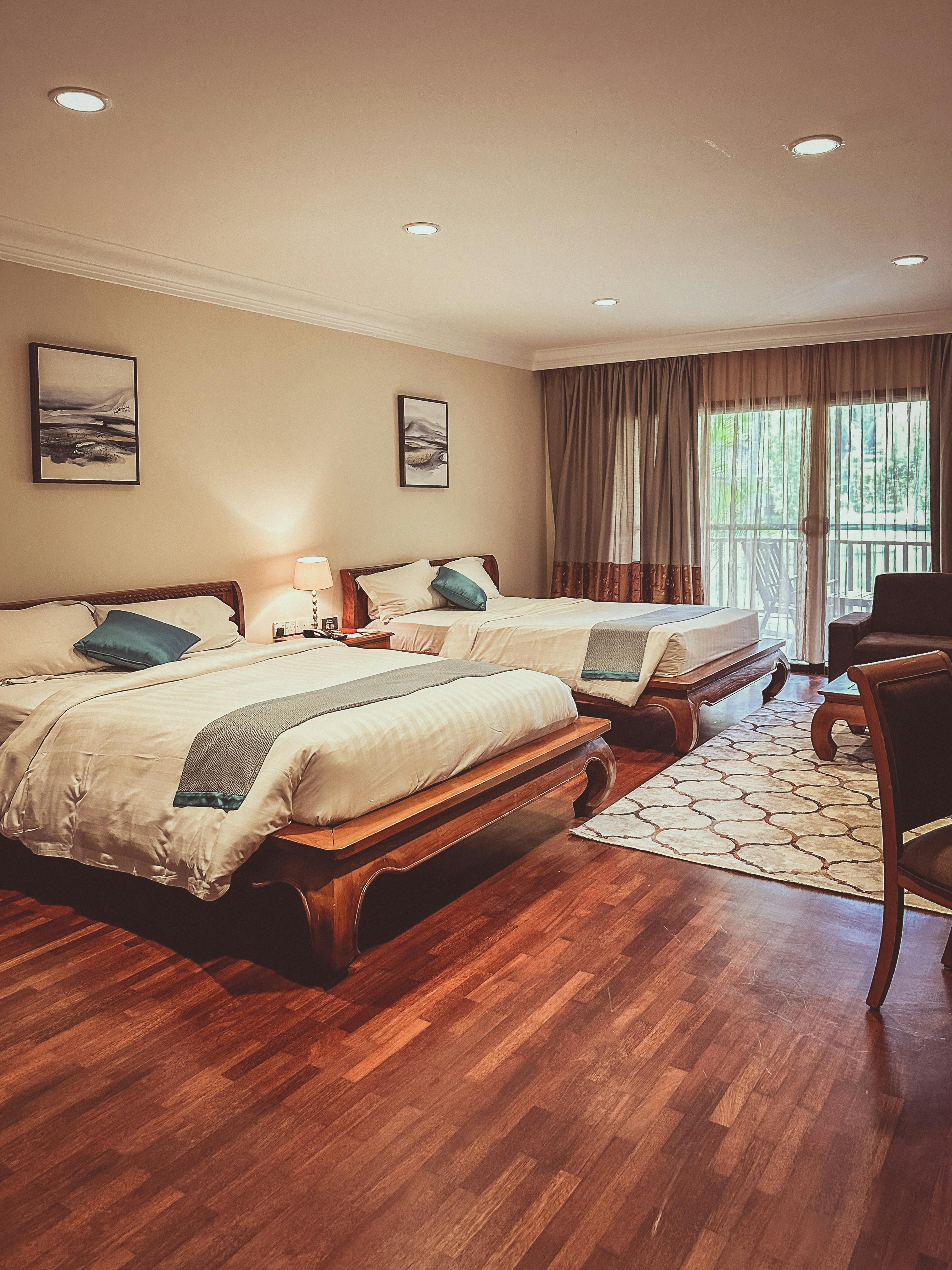 Spacious hotel room with two beds, wood flooring, and elegant decor. Ideal for leisure stays.