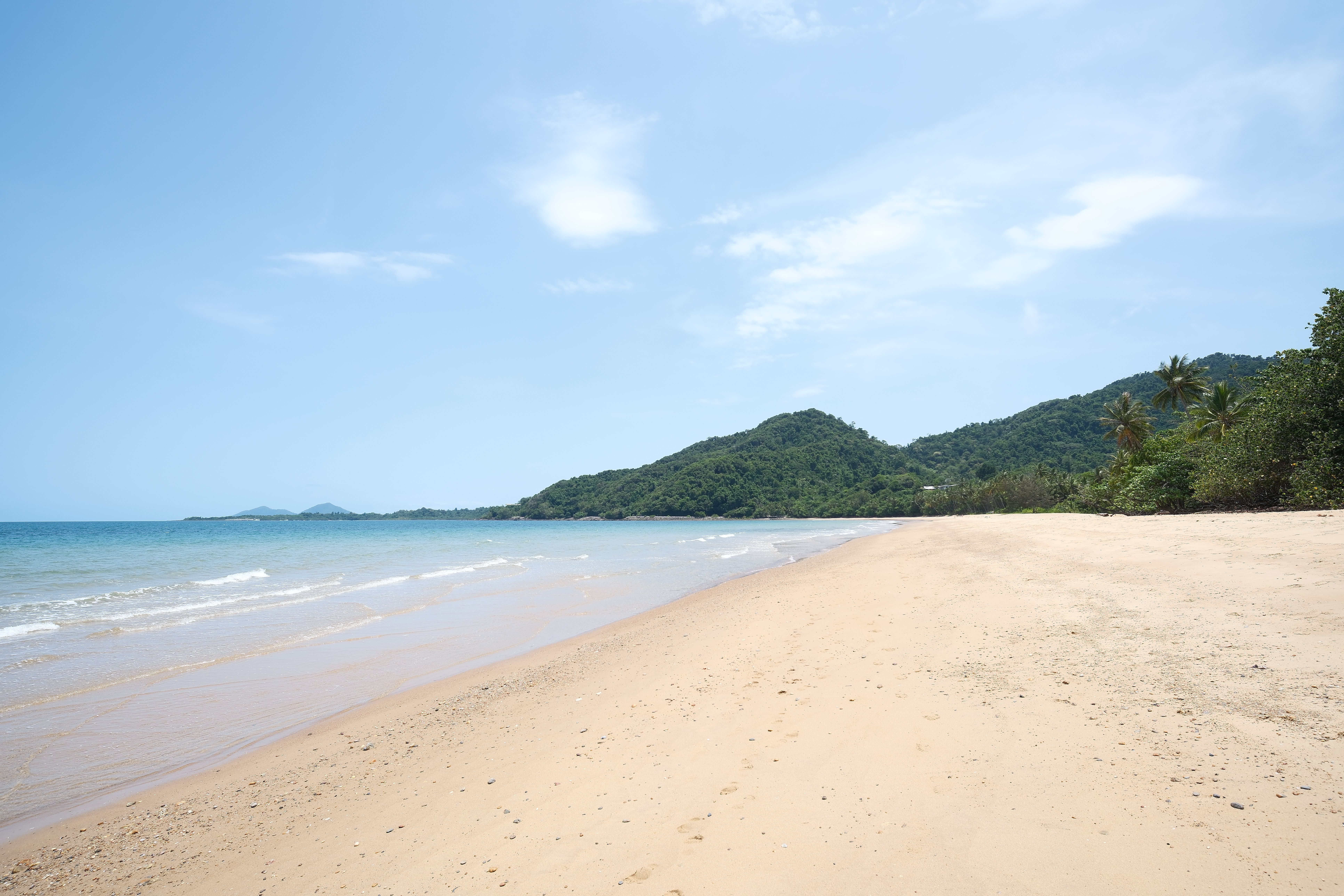 A quiet golden-sand beach backed by green hills on the Gulf of Thailand