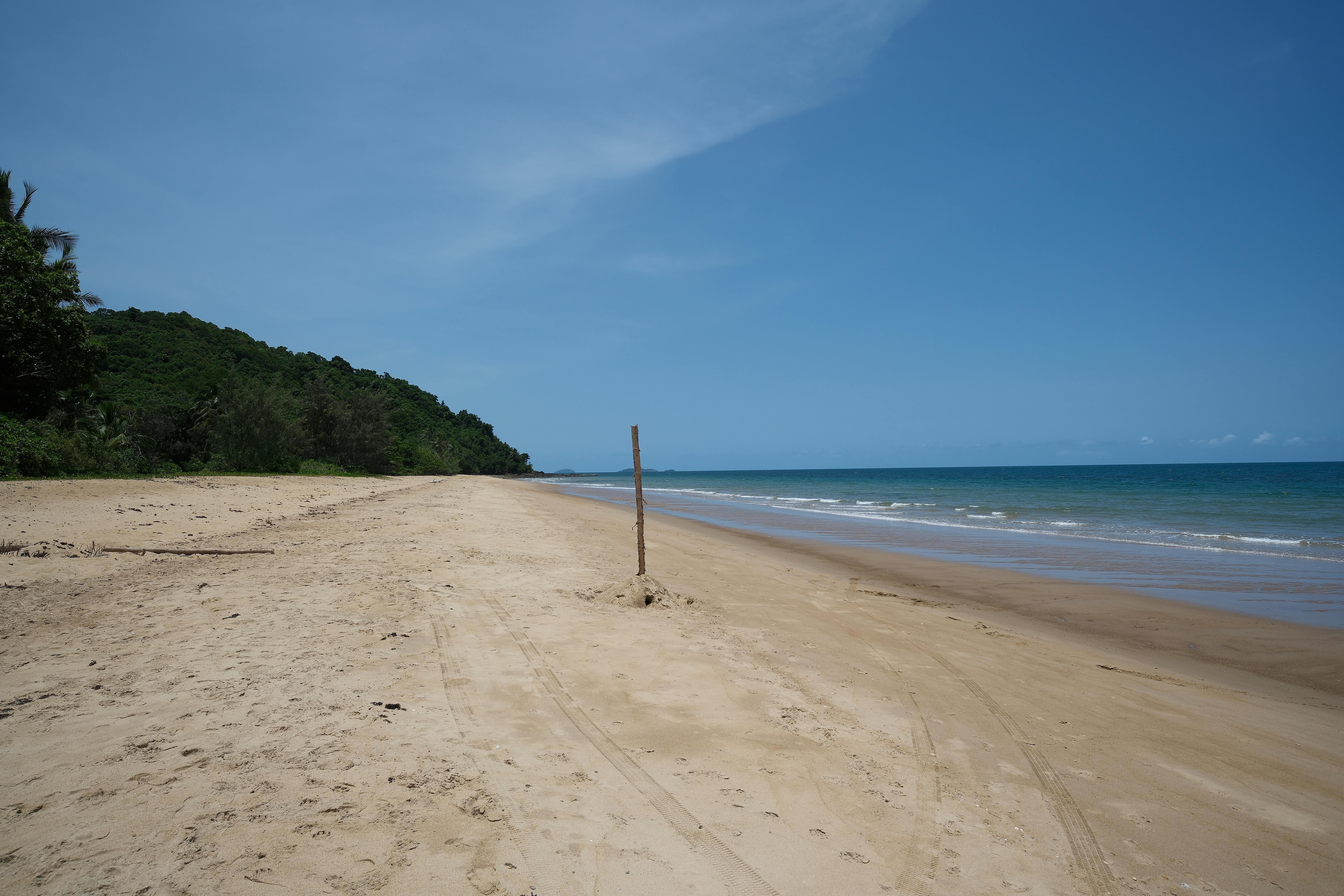 A tranquil tropical beach with golden sand and clear blue sky, perfect for relaxation and travel.