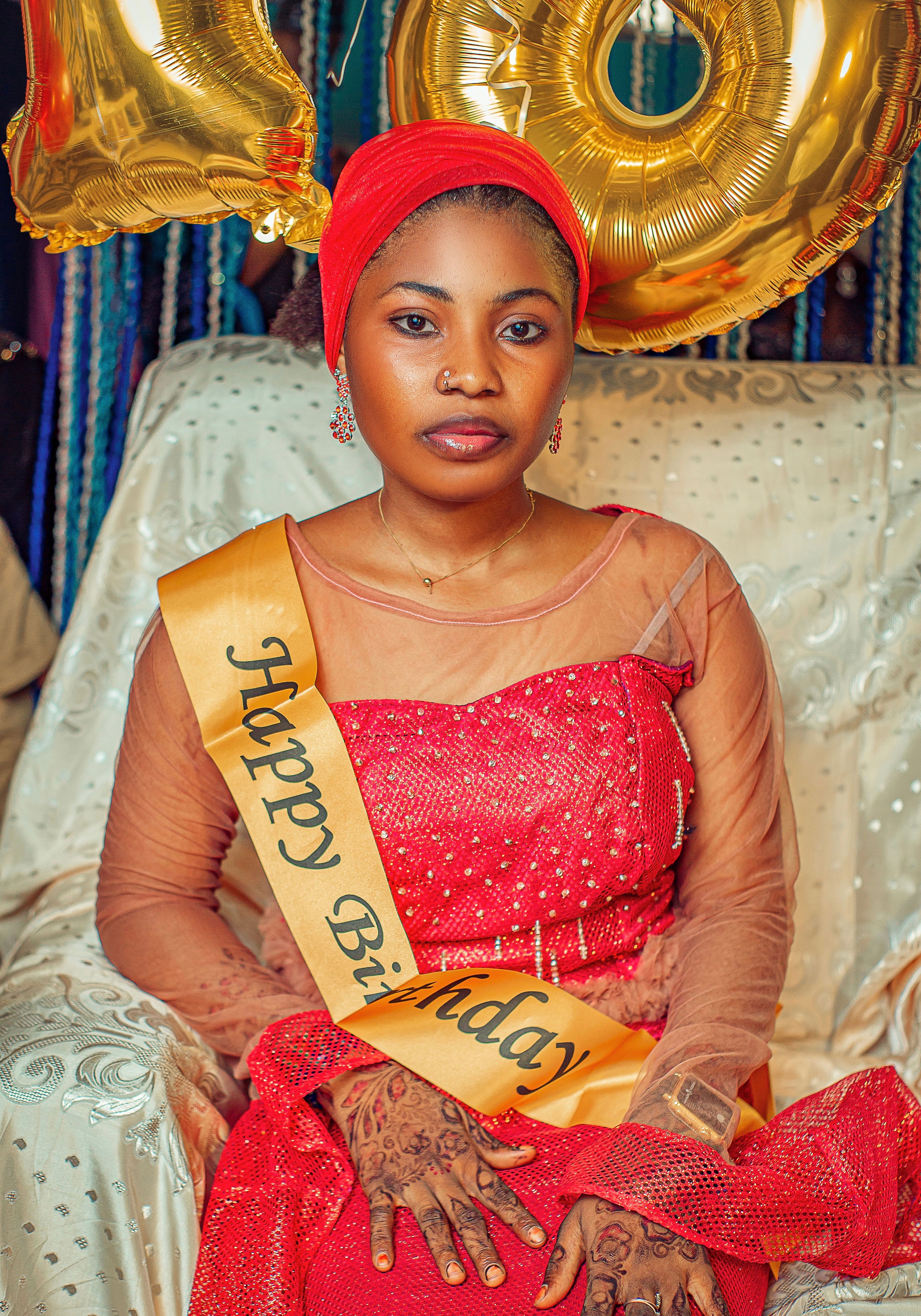 Young woman in cultural attire celebrates birthday, sitting with decorations.