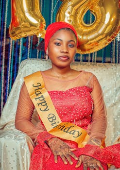 Young woman celebrating her birthday with golden balloons and vibrant attire.