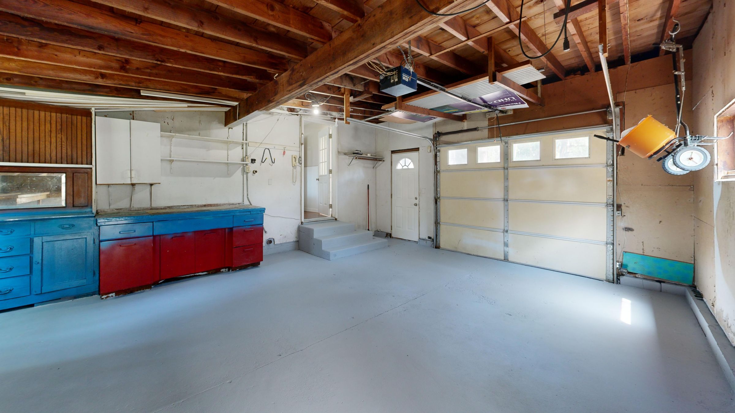Small garage with open floor space, wall cabinets, and clear walking paths around a parked vehicle