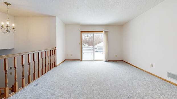 Bright empty living room with carpet and chandelier, ready for new decor.