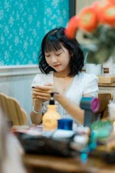 A young woman attentively using her smartphone in a cozy indoor setting, surrounded by colorful objects.
