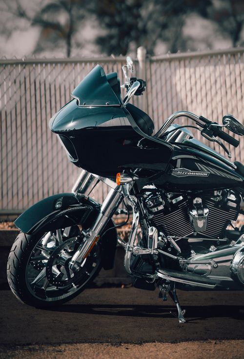 Free A detailed view of a shiny black touring motorcycle parked in front of a chain-link fence. Stock Photo