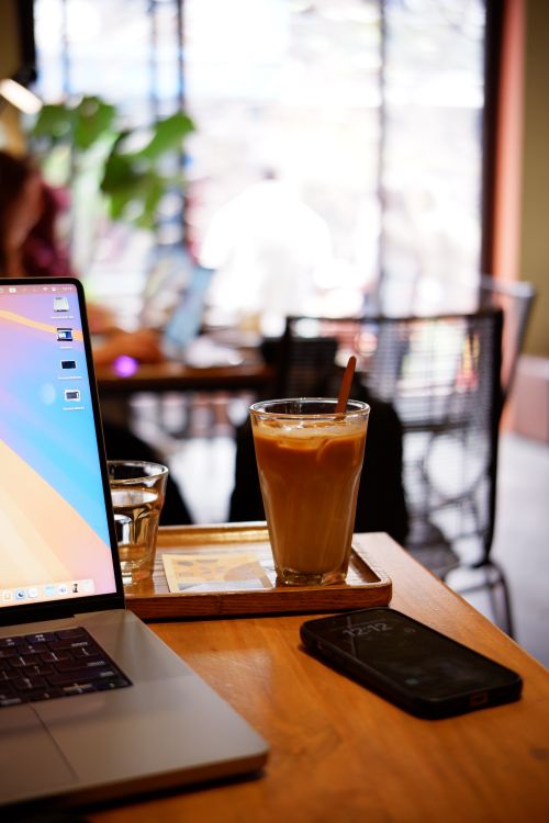 Free Refreshing iced coffee placed on a wooden table in a contemporary café setting, perfect for work or leisure. Stock Photo