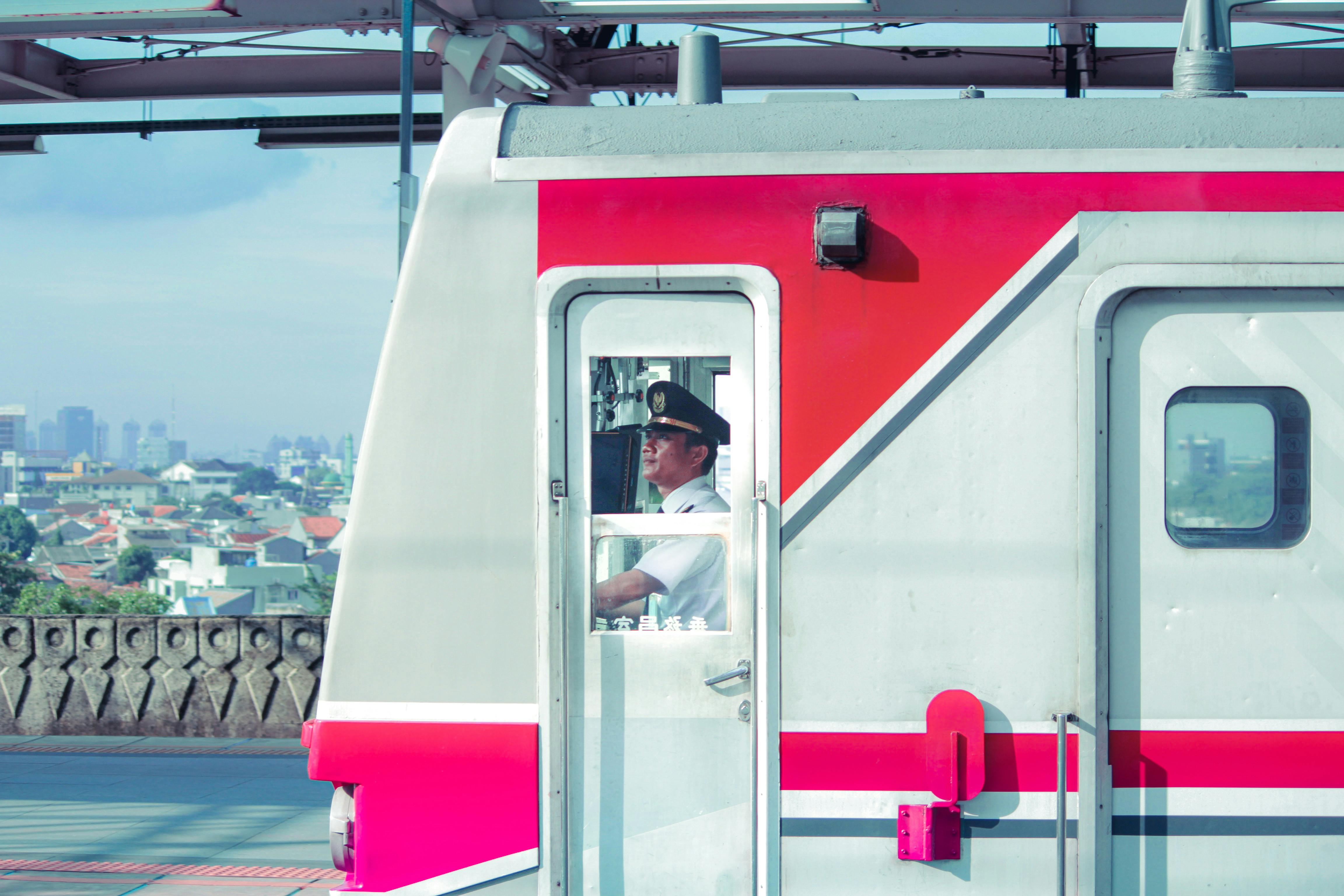 Train conductor focused on driving a city train amidst an urban backdrop.