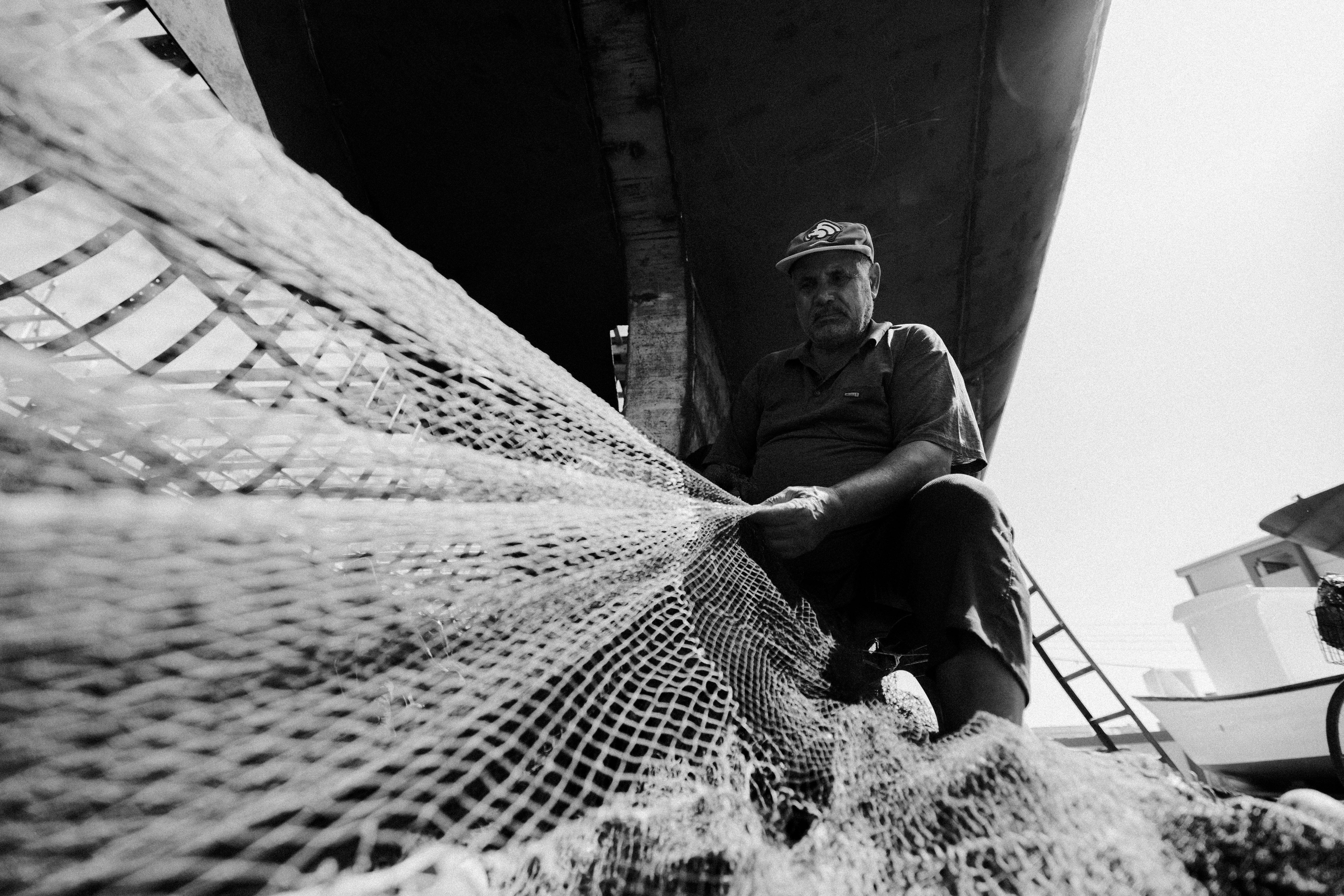 Fisherman Repairing Net under Boat in Damietta · Free Stock Photo