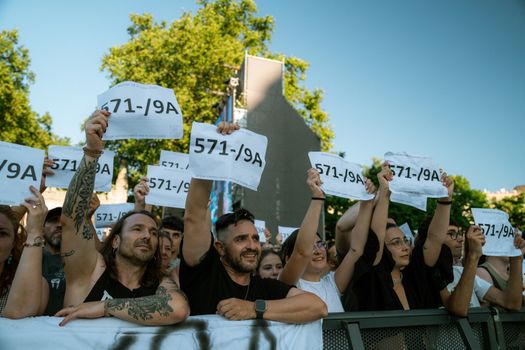 Diverse crowd holding numbered signs at an outdoor event in sunlight. Unity and expression.