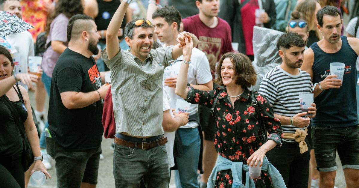 A lively group of adults enjoying a vibrant outdoor festival with music and drinks.