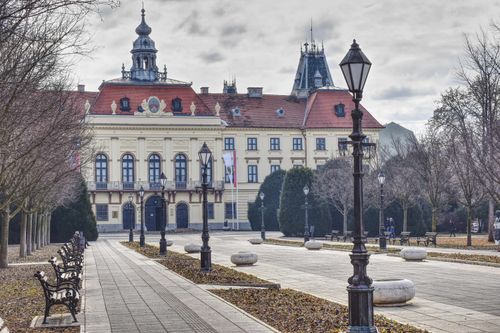 Free Elegant historic building with red roof and spires in a tranquil European city square. Stock Photo