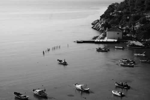 Free Black and white photo of boats near a cliffside house, evoking tranquility. Stock Photo