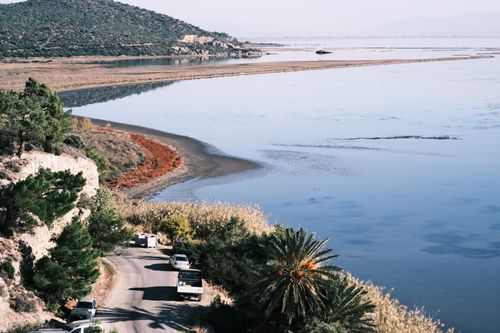 Free Aerial view of cars driving along a scenic coastal road by a tranquil blue lake. Stock Photo