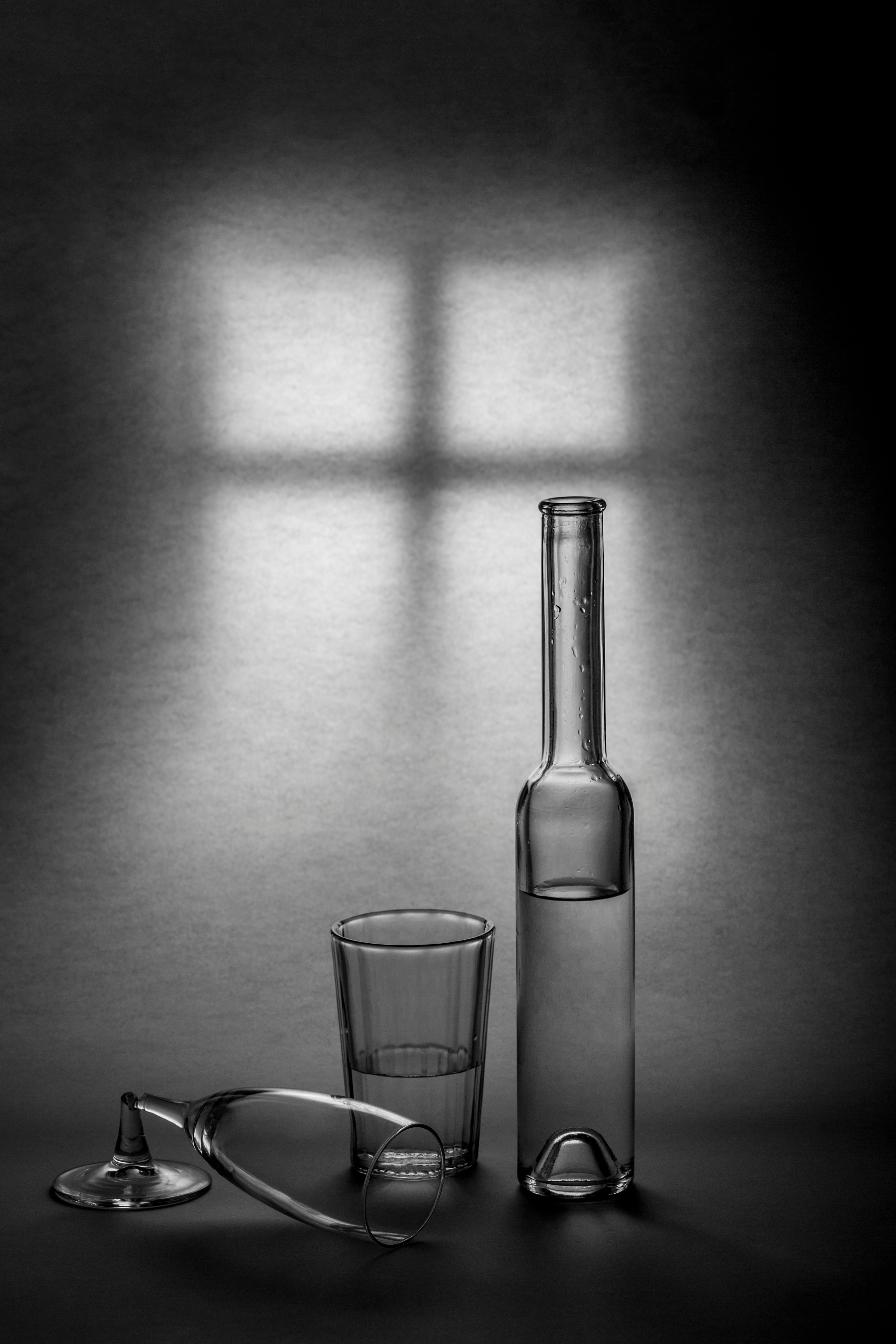 Artistic black and white still life featuring glass bottles and shadows.