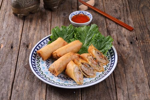 Free Delicious homemade spring rolls served with a spicy dipping sauce on a rustic wooden table, perfect for appetizers. Stock Photo